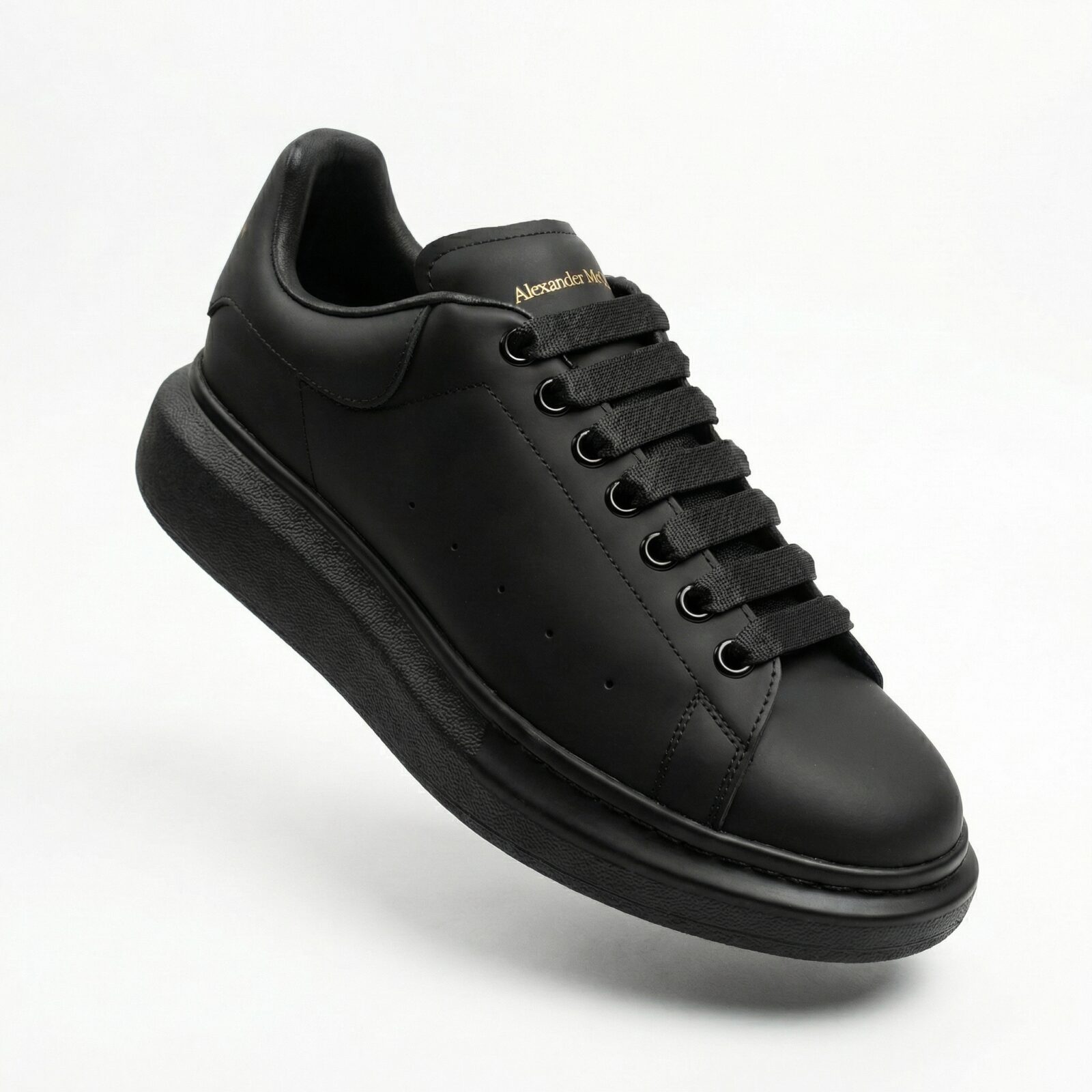 Alexander McQueen Oversized Black Sneakers Front Angle Gold Logo - SHUZAR Egypt